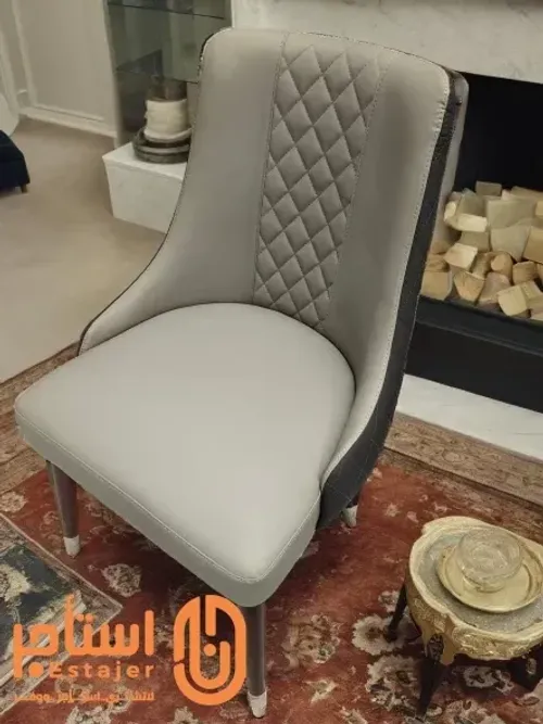 كرسي عصري بتصميم أنيق ومريح ومغطى بجلد فاخر باللون الرمادي،مع تفاصيل منجدة بنمط ماسي على الجزء الخلفي.2